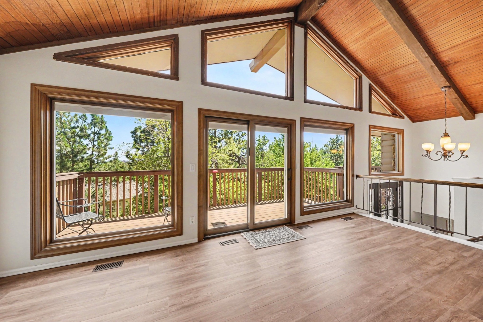 Living room with Pella picture windows and angled clerestory glass under a vaulted wood ceiling